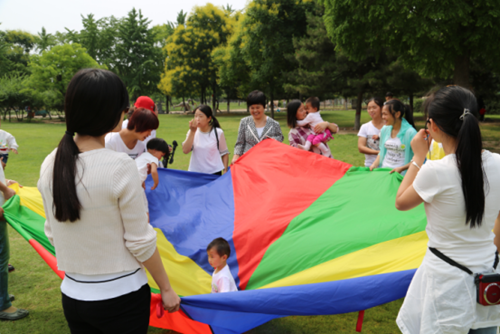 图为濮阳市康教中心聋儿、家长及教师正在开展“彩虹伞”游戏活动现场