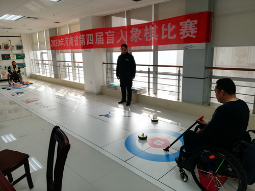 图为：教练员在指导轮椅旱地冰壶运动员训练