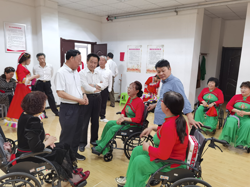 图为：洛阳市残联党组成员、副理事长张国美与残疾人朋友亲切交谈