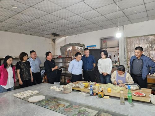 图为：杭州市残联考察学习团一行人参观三彩工艺品生产车间