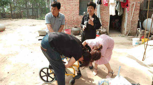 图为：市残联副理事长张湘鄂一行入户为贫困残疾儿童免费发放儿童轮椅