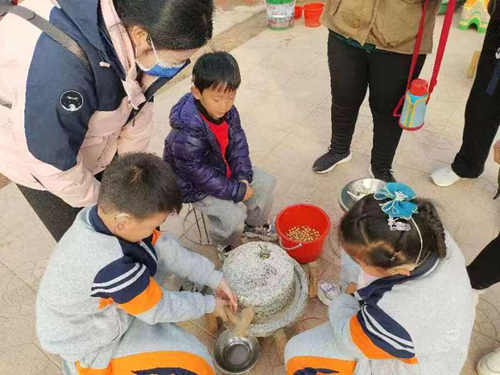 图为在寿星庄听障儿童学习怎样磨豆浆