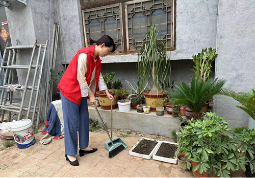 图为志愿者帮助残疾人打扫庭院卫生