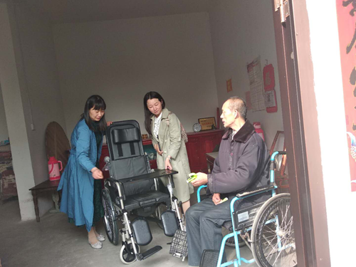 图为工作人员为贫困重度残疾人适配轮椅及辅助器具
