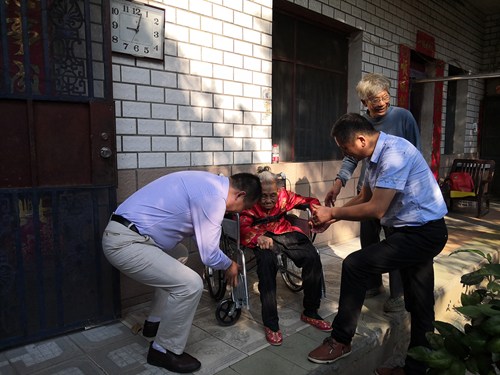 图为李青理事长为百岁老人调试轮椅