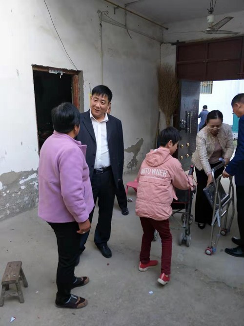 图为西华县残联“四话”活动理事长王仕民与残疾儿童家长拉家常