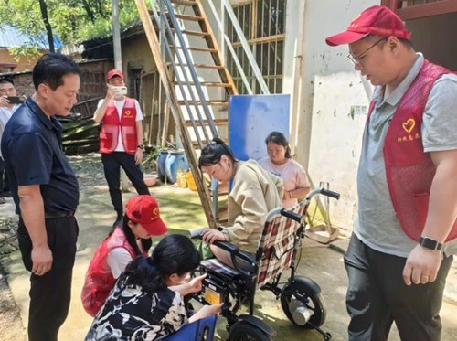 图为：志愿者向杨阳讲解轮椅的使用方法